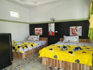 two beds in a room with yellow sheets with dogs on them at สิชล บ้านอุ๊ รีสอร์ท in Sichon