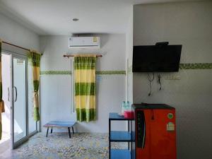een kamer met een tv en een stoel in een kamer bij สิชล บ้านอุ๊ รีสอร์ท in Sichon