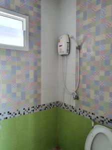 een badkamer met een douche, een toilet en een raam bij สิชล บ้านอุ๊ รีสอร์ท in Sichon