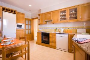 una cocina con electrodomésticos blancos y armarios de madera en Villa Manuel by Villa Plus en Son Parc
