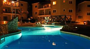 uma grande piscina com água azul à noite em Sirena Olympia Apartment 40 em Pafos