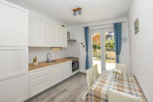 a kitchen with white cabinets and a table with chairs at Apartments Dragica in Primošten