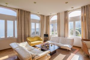 salon z białymi meblami i dużymi oknami w obiekcie L'Ambassadeur - Magnifique appartement dans l'ancien hôtel Ar Vro w mieście Saint-Cast-le-Guildo