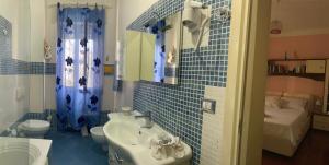 een blauw betegelde badkamer met een wastafel en een toilet bij B&B Shabby Chic in Alghero