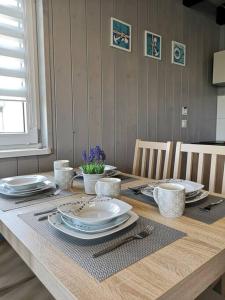 einem Holztisch mit Tellern und Utensilien darauf in der Unterkunft Słoneczny Raj Apartamenty Domki apartamentowe in Sarbinowo