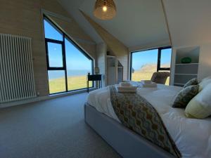 a bedroom with a large bed with large windows at 5 Bedroom Cottage - Llyn Peninsula in Pistyll