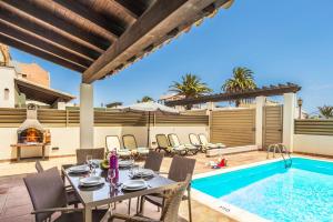 un patio con mesa y sillas junto a una piscina en Villa Nanda by Villa Plus en Corralejo