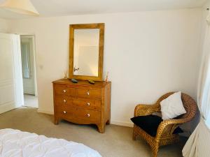 a bedroom with a dresser and a mirror and a chair at Stylish apartment - 2 min walk from Ogmore by sea beach with private garden, sea views & stunning sunsets, dog friendly in Tythegston