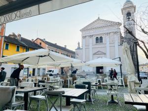 un gruppo di tavoli e ombrelloni di fronte a un edificio di Osteria Pozzo a Locarno