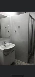 a white bathroom with a sink and a shower at Siódme Niebo-komfortowe pokoje nad samym morzem in Stegna
