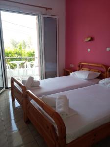 Duas camas num quarto com uma janela grande em Villa Nikitas em Parga