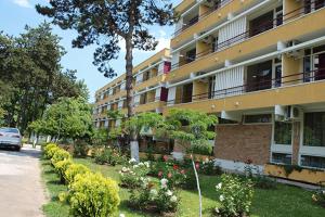 a large apartment building with a garden in front of it at Hotel Sara in Neptun