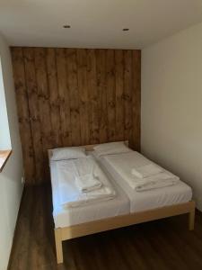 a bed in a room with a wooden wall at Apartmany Milano s výrivkou a terasou in Kvakovce