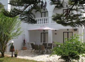 een wit huis met een tafel en een paraplu bij Rodis Studios in Tsilivi