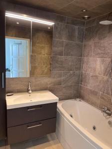 La salle de bains est pourvue d'un lavabo, d'une baignoire et d'un miroir. dans l'établissement Comfortabele woning mét omheinde tuin aan water voor 12 p, à Oostbourg
