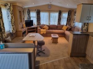 a living room with a couch and a table at 8 BERTH DELUXE PG153 GOLDEN PALM CHAPEL ST LEONARDS in Chapel Saint Leonards