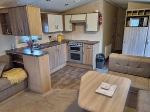 a kitchen and living room with a couch and a table at 8 BERTH DELUXE PG153 GOLDEN PALM CHAPEL ST LEONARDS in Chapel Saint Leonards