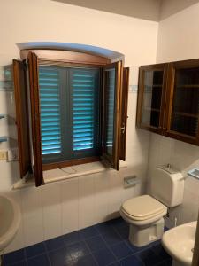 a bathroom with a toilet and a window with blue shutters at Casa Musa in Capannori