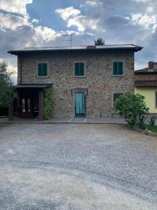 a stone house with a green door and a gravel driveway at Casa Musa in Capannori