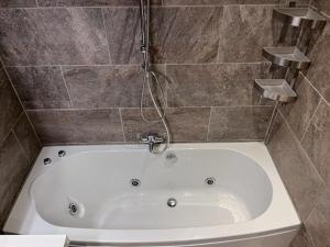 eine weiße Badewanne im Bad mit einer Kachelwand in der Unterkunft Comfortabele woning mét omheinde tuin aan water voor 12 p in Oostburg + 17 Fotos