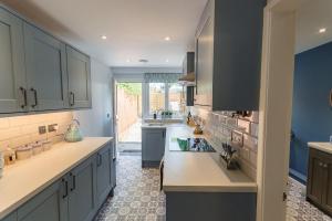 a kitchen with blue and white cabinets and a sink at Lavender Cottage - Knodishall - Newly renovated 2 bed holiday home, near Aldeburgh, Leiston and Thorpeness in Aldringham