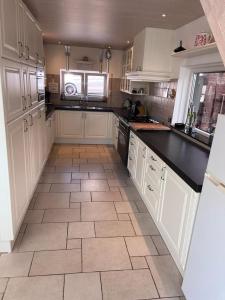 a kitchen with white cabinets and a tile floor at Comfortabele woning mét omheinde tuin aan water voor 12 p in Oostburg