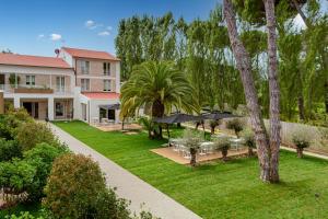 a garden with tables and umbrellas and a building at Resort Miramonti in Forte dei Marmi