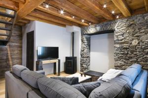 sala de estar con sofá y pared de piedra en Luderna - Casa Les er Haro, en Les