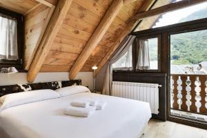a bedroom with a large white bed with wooden ceilings at Luderna - Casa Les er Haro in Les