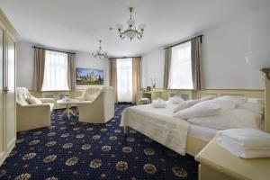 una habitación de hotel con una cama grande y sillas en Hotel Podhrad en Hluboká nad Vltavou