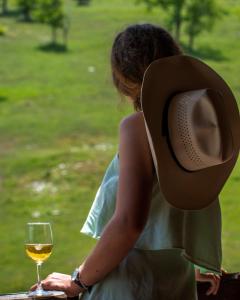 a woman with a hat and a glass of wine at Etno Village Vojnik in Šavnik