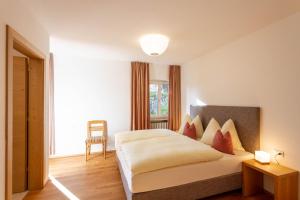 een slaapkamer met een wit bed met rode kussens bij Haus Lohengrin Ferienwohnung 1 in Siusi