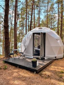 a tent with a wooden deck in the woods at Skywoods.glamping in Molėtai