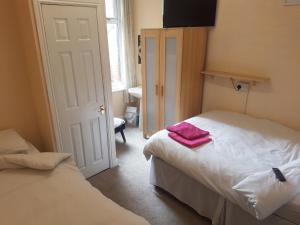 a bedroom with two beds with pink towels on them at Leecliff Guest House in Blackpool
