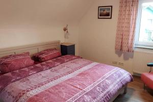 1 dormitorio con cama con sábanas rosas y ventana en gemütliche Ferienwohnung auf 2 Etagen mit Dachterrasse, en Wangen im Allgäu