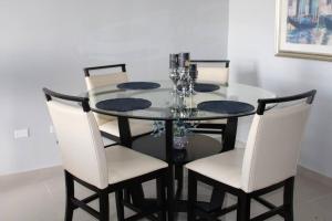 a dining room table with white chairs and a glass table at Penthouse Views in San Juan