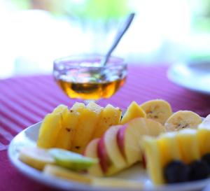 a plate of fruit on a table with a bowl of honey at Sea Star Beach Homes in Cherai Beach