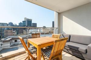 een houten tafel en stoelen op een balkon met een bank bij Mandela Rhodes Luxury Apartments in Kaapstad