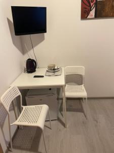 a white desk with two chairs and a television on a wall at Pokoje Sztormowa 15 in Pogorzelica