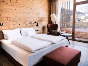 una camera da letto con un letto, una sedia e una finestra di Falkensteiner Hotel Schladming Superior a Schladming