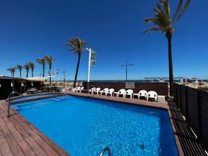 a swimming pool with chairs and palm trees at Hotel Hey Peñíscola in Peniscola