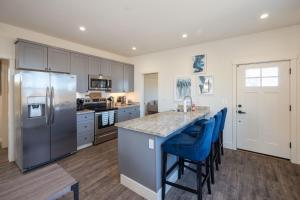 a kitchen with stainless steel appliances and blue bar stools at Beach Town Home wHot Tub - Walk to Beaches Downtown Activities and more in Half Moon Bay
