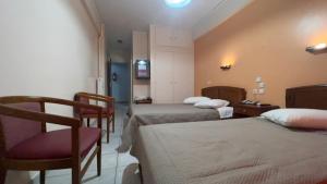 a hotel room with two beds and a chair at Hotel Cosmos in Athens
