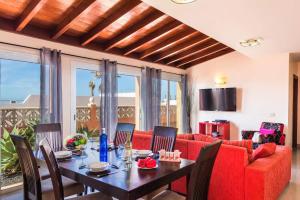 una sala da pranzo con tavolo e divano rosso di Villa Tamarindos by Villa Plus a La Oliva