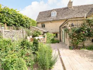 an old stone house with a garden in front of it at Rood Cottage in Burford