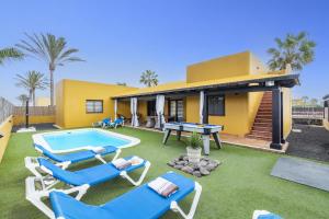 eine Villa mit einem Pool, Stühlen und einem Haus in der Unterkunft Villa Papagayo Deluxe by Villa Plus in Corralejo