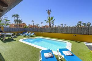 a swimming pool with lounge chairs and a fence at Villa Papagayo Deluxe by Villa Plus in Corralejo