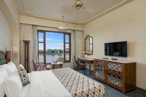 a bedroom with a bed and a television and a desk at Brahma Niwas - Best Lake View Hotel in Udaipur in Udaipur