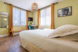 1 dormitorio con 1 cama blanca grande y ventanas en Hôtel Cosmopolitain, en Biarritz