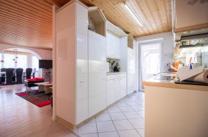 cocina con armarios blancos y techo de madera en Haus Padrun, Apartment nr.8, en Arosa